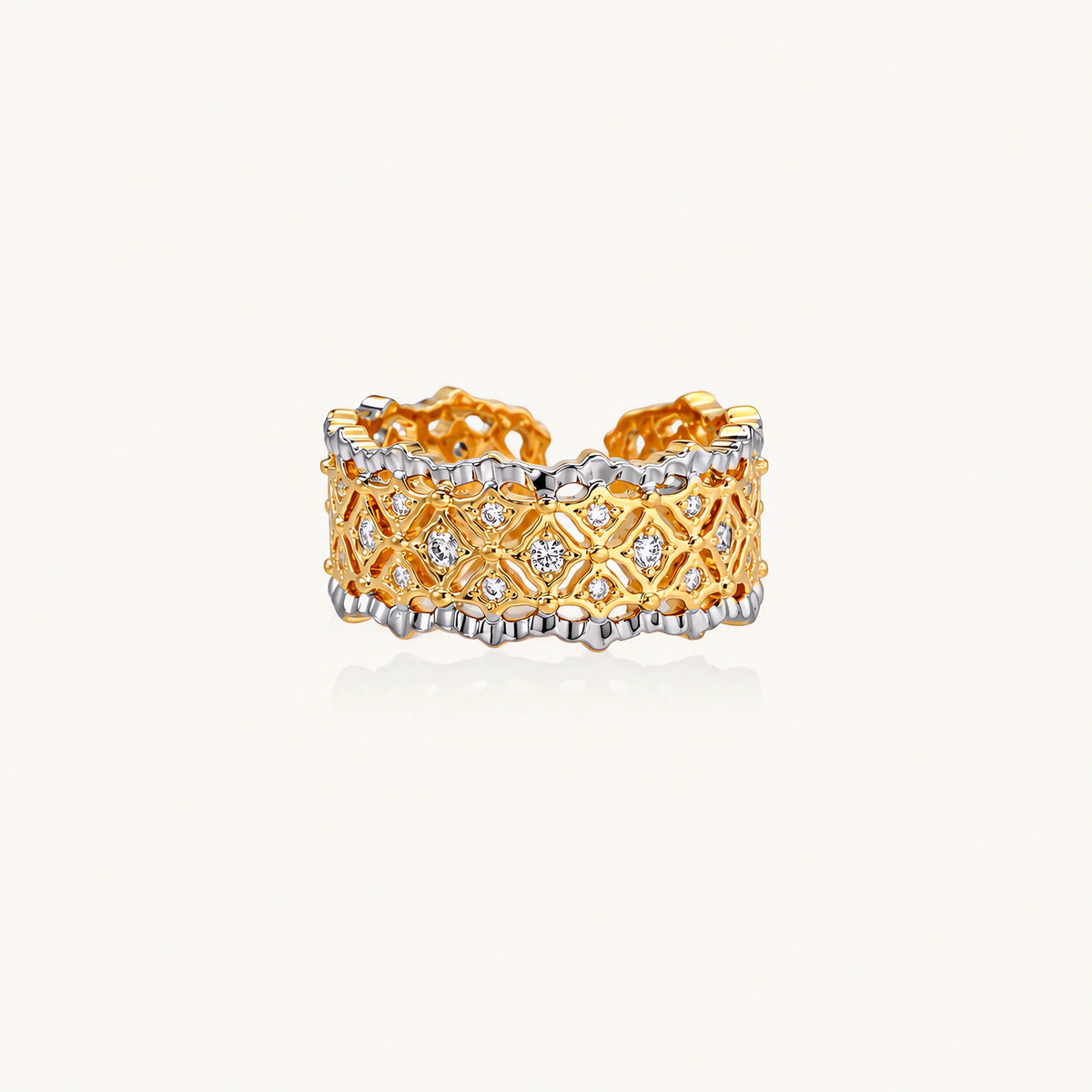 Two-tone ring with geometric lattice pattern in gold and silver finish with crystal accents on beige background