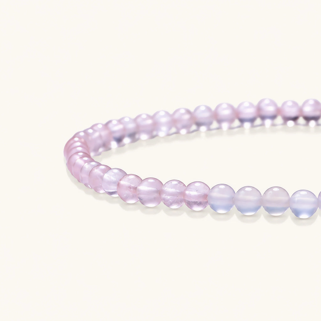 Double-wrap lavender beaded bracelet with rose quartz, pearls, gold vermeil charm and pink tassel on white background.