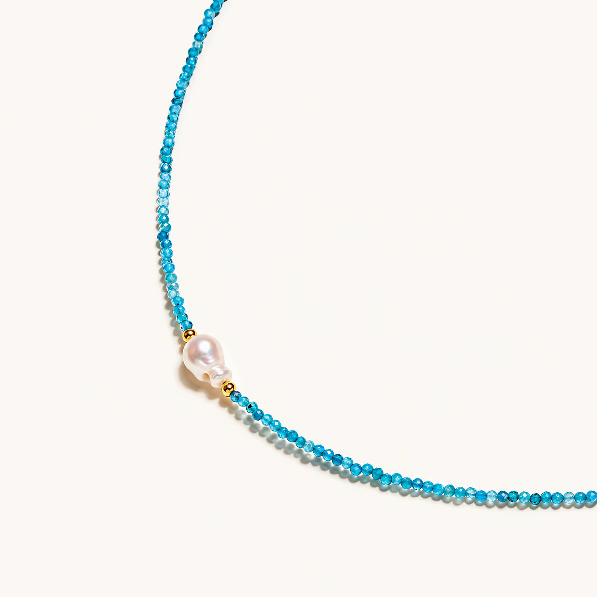 Dainty teal apatite beaded necklace with a single freshwater pearl centerpiece flanked by two small gold beads, adjustable gold clasp.