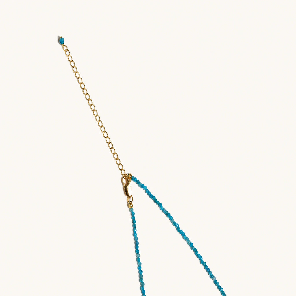 Dainty teal apatite beaded necklace with a single freshwater pearl centerpiece flanked by two small gold beads, adjustable gold clasp.
