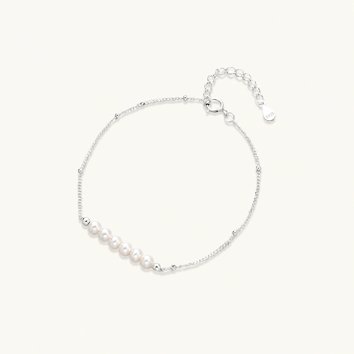 Delicate rhodium-plated silver chain bracelet with row of small baroque pearls centered on white background.