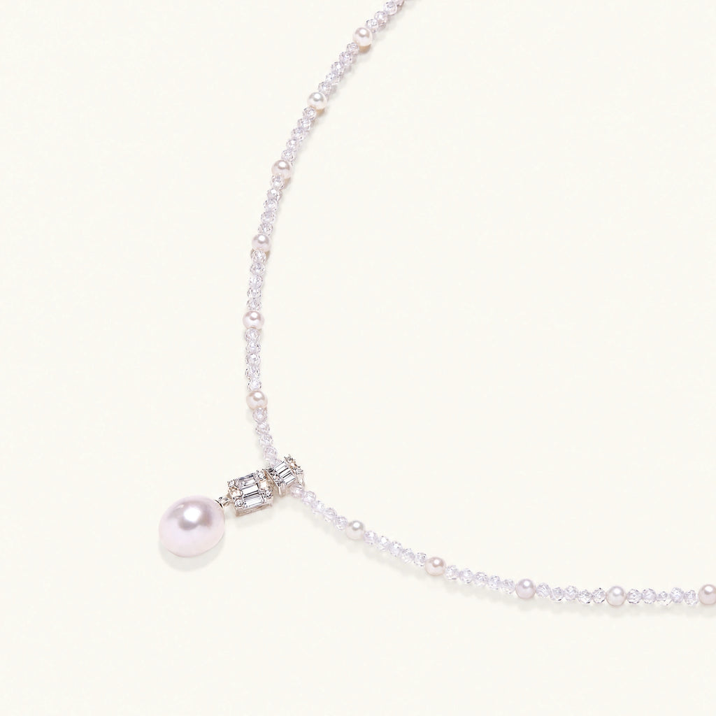 Dainty necklace with lavender crystal beads, freshwater pearls, geometric pendant, and large pearl drop on white background.