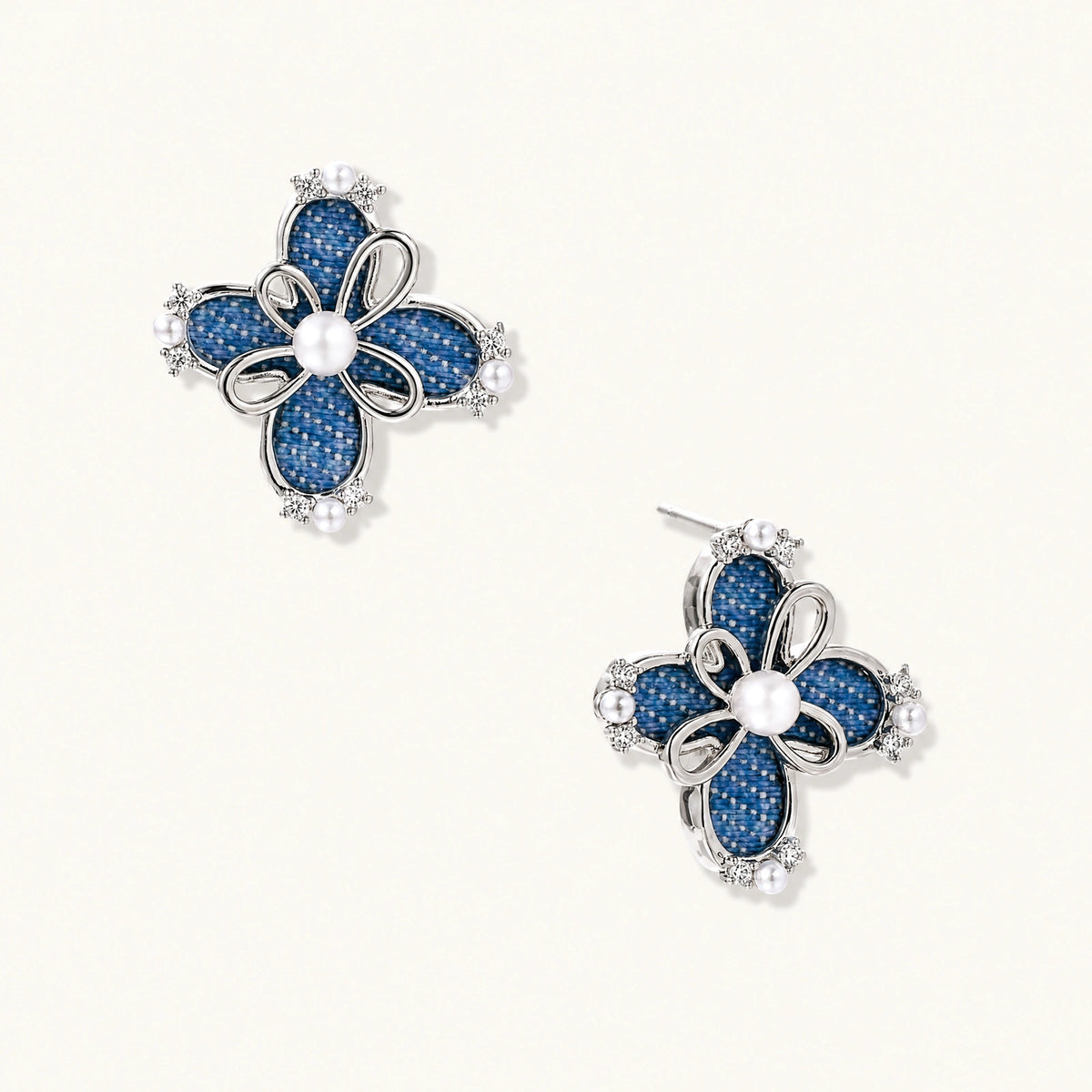 Pair of silver-tone four-petal flower stud earrings with blue denim fabric petals, a center white bead and zirconia accents.