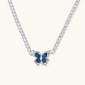 White gold plated tennis necklace with blue denim butterfly pendant and clear zirconia stones on cream background