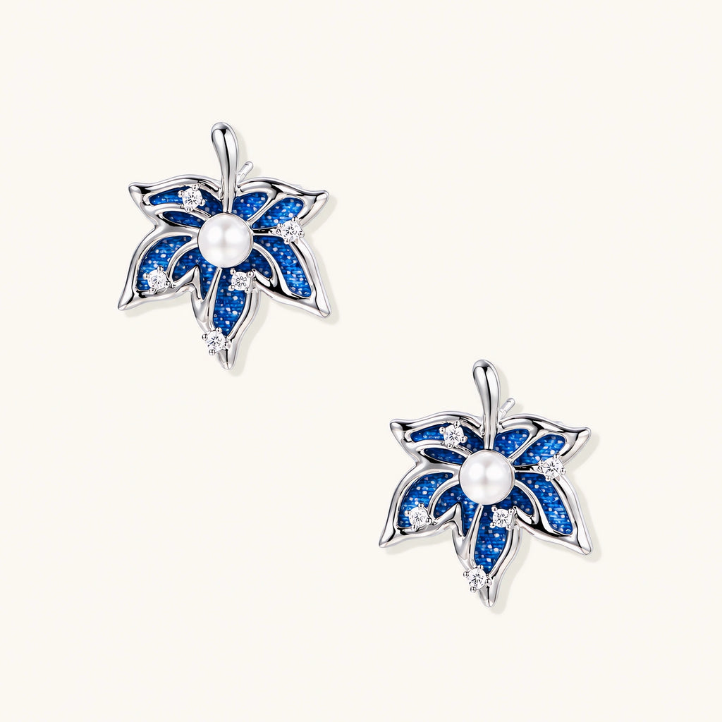 Pair of maple leaf stud earrings with blue denim fabric, a white bead center and zirconia accents in white gold plated eco-brass.