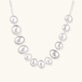 Sterling silver necklace with fourteen matte concave round and oval discs on a curb chain with an adjustable extender.