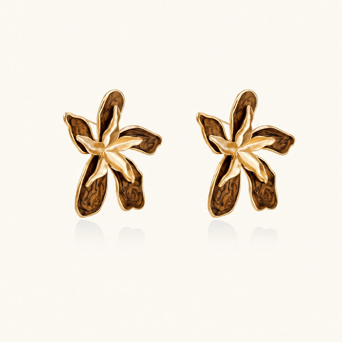 Gold-plated brass flower earrings with brown tortoiseshell enamel petals on cream background