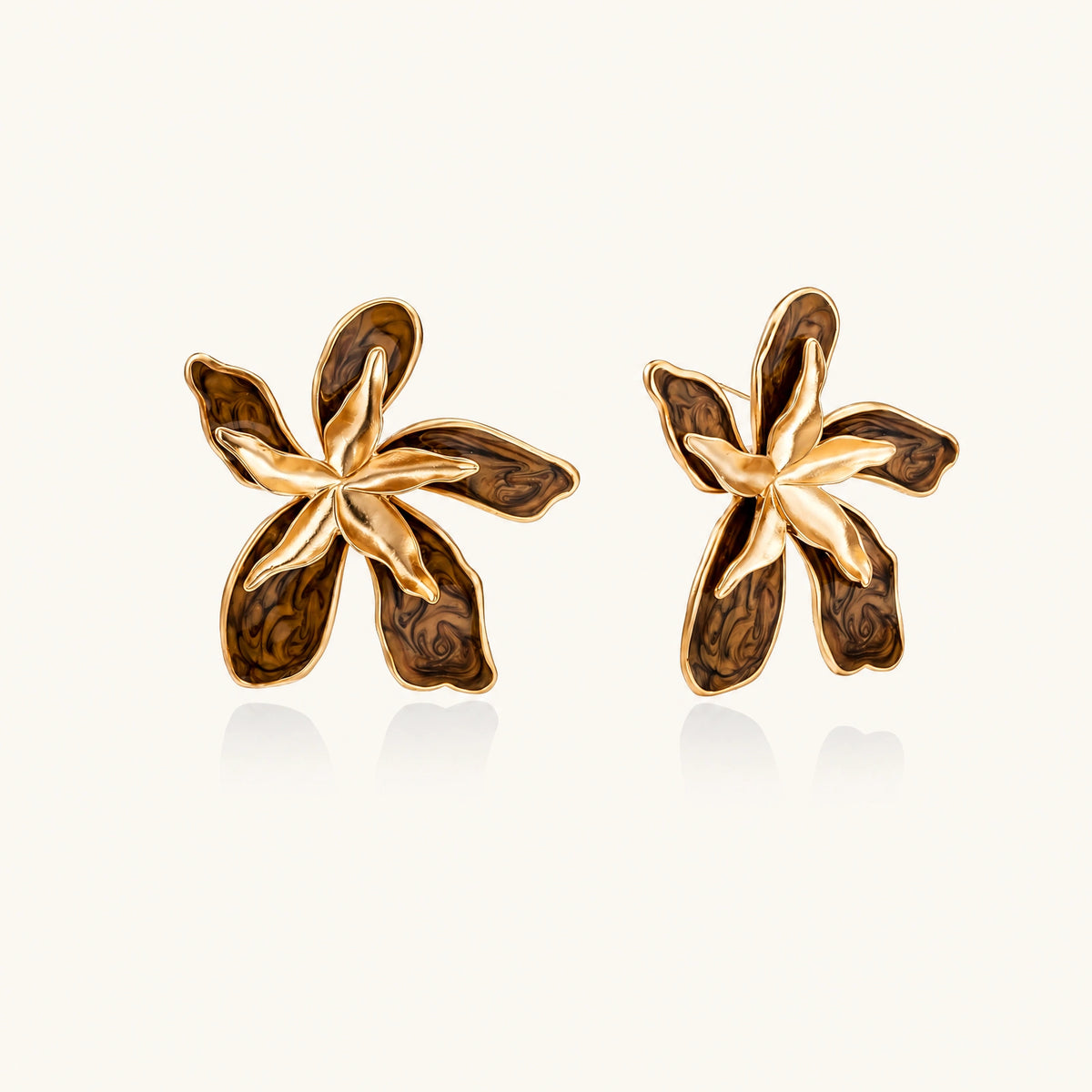 Gold-plated brass flower earrings with brown tortoiseshell enamel petals on cream background