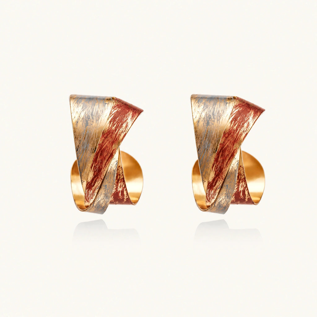 Sculptural gold-plated hoop earrings with diagonal purple and coral enamel stripes in twisted ribbon design