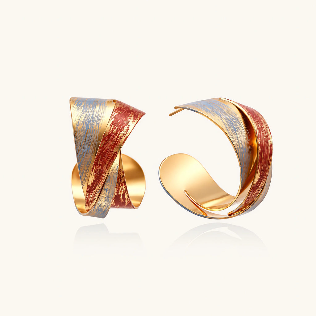 Sculptural gold-plated hoop earrings with diagonal purple and coral enamel stripes in twisted ribbon design