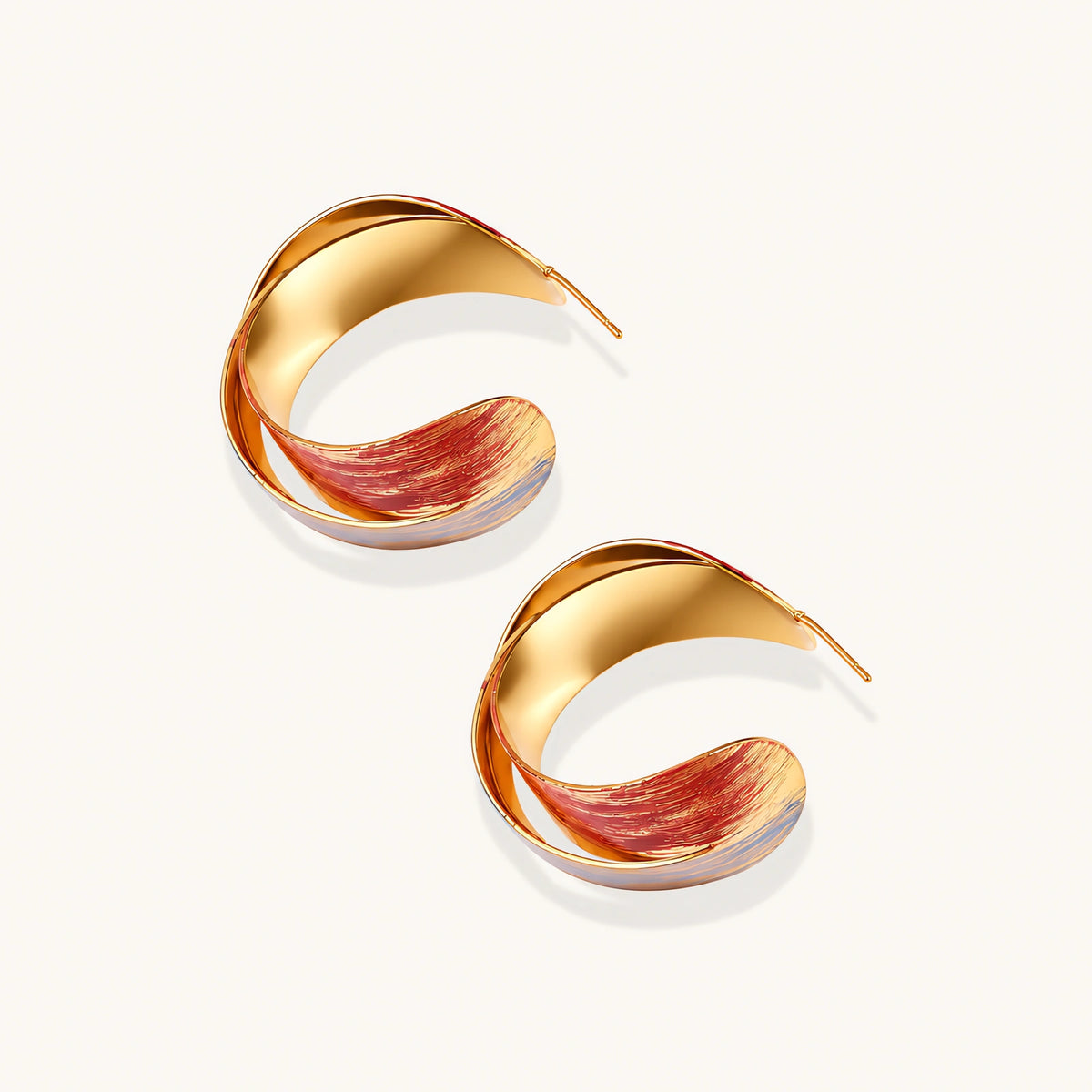 Sculptural gold-plated hoop earrings with diagonal purple and coral enamel stripes in twisted ribbon design