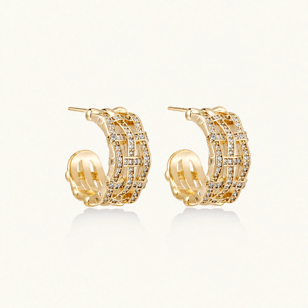 Gold-plated geometric hoop earrings with basket-weave lattice design and pavé crystal accents on cream background