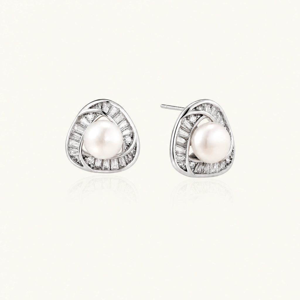 Triangular white gold plated stud earrings with central freshwater pearl and baguette-cut stones on white background