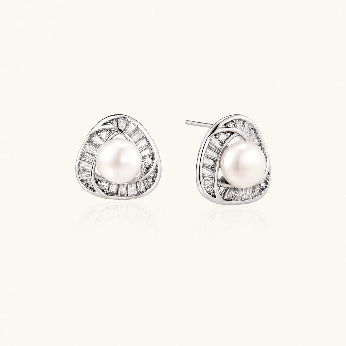 Triangular white gold plated stud earrings with central freshwater pearl and baguette-cut stones on white background