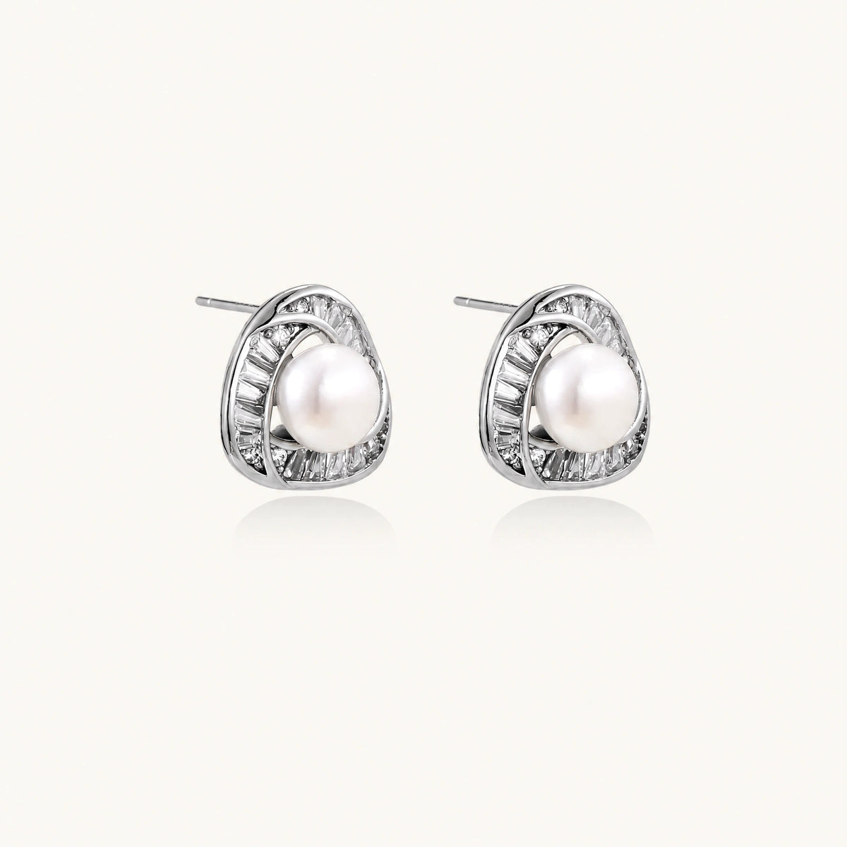 Triangular white gold plated stud earrings with central freshwater pearl and baguette-cut stones on white background