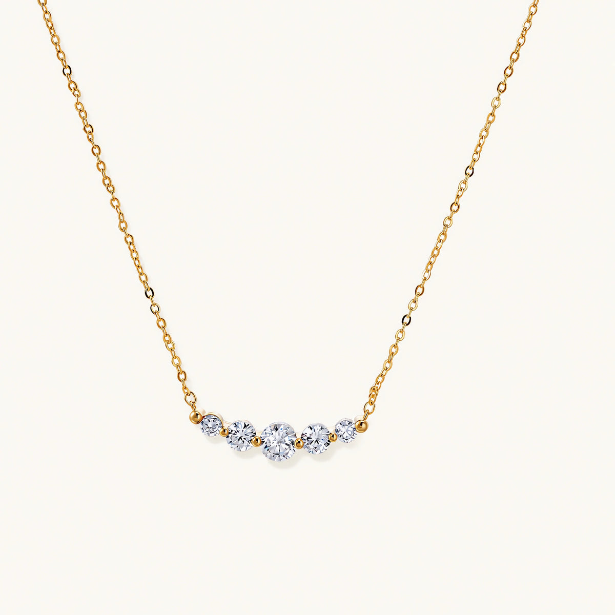 Delicate 14K gold-plated necklace with five graduated zirconia stones arranged in a curved arc on fine chain