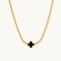 Dainty 18K gold-plated herringbone chain necklace with black enamel quatrefoil clover pendant on white background