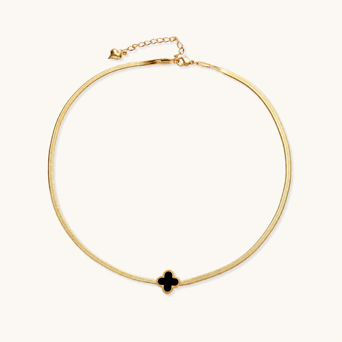 Dainty 18K gold-plated herringbone chain necklace with black enamel quatrefoil clover pendant on white background