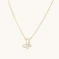 Gold-plated butterfly pendant with iridescent mother of pearl inlay on delicate chain against cream background.