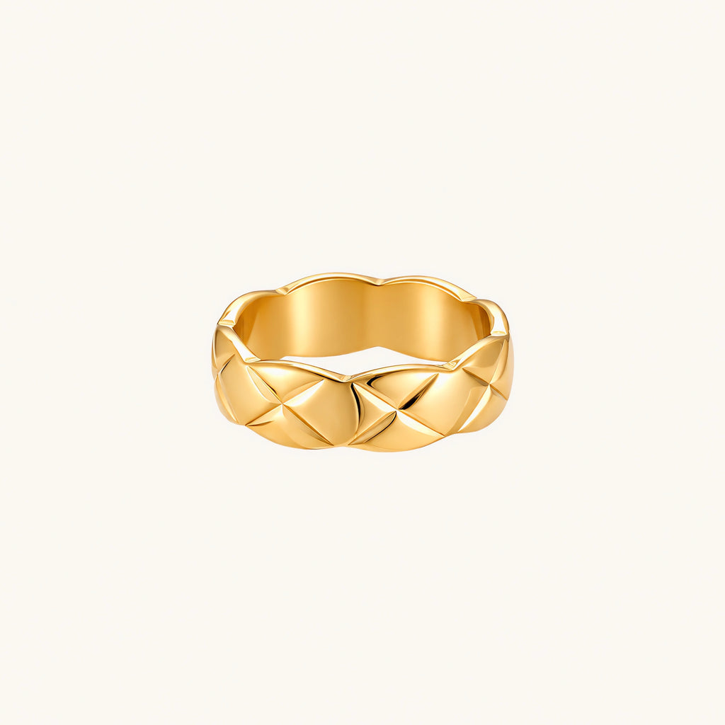 Close-up of an 18K gold-plated twisted band ring with dimensional braided pattern on cream background.