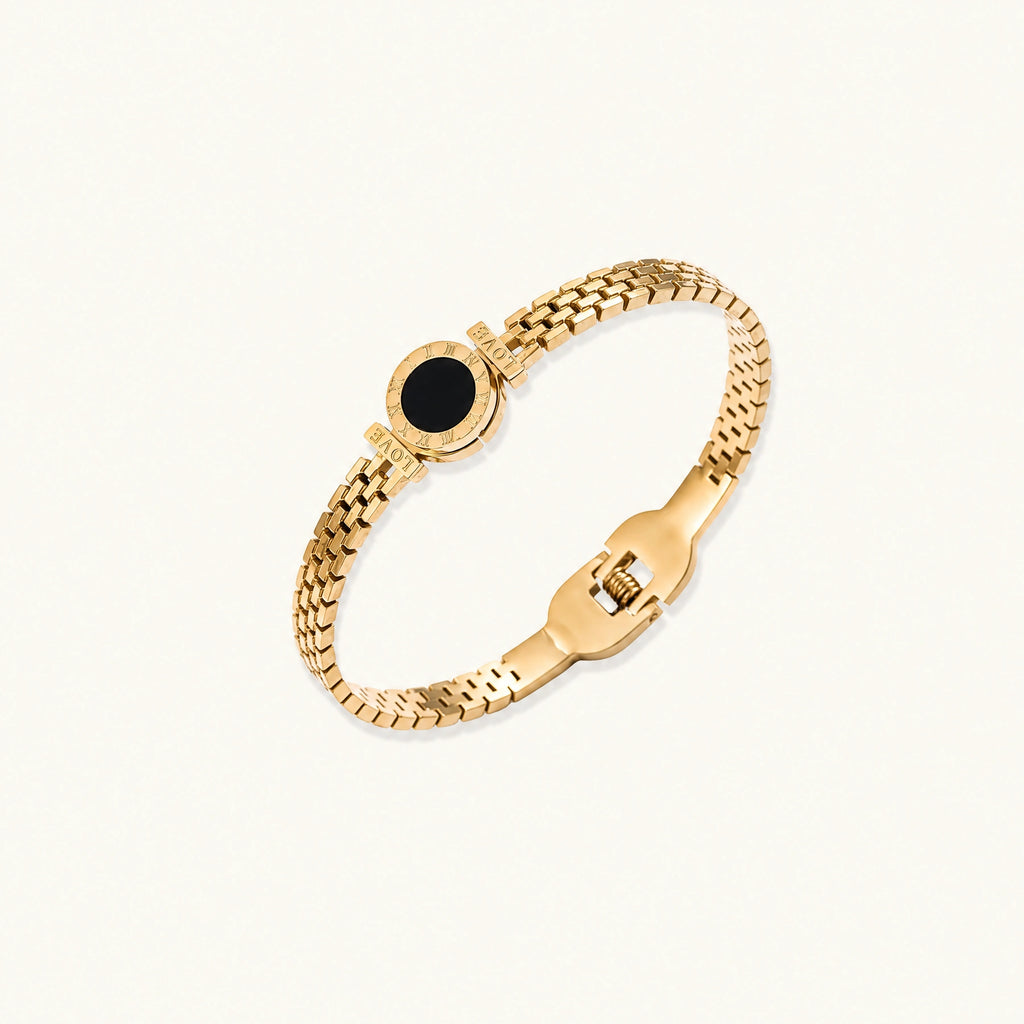 Gold mesh bracelet with circular black mother of pearl medallion featuring Roman numeral engravings and hinged clasp