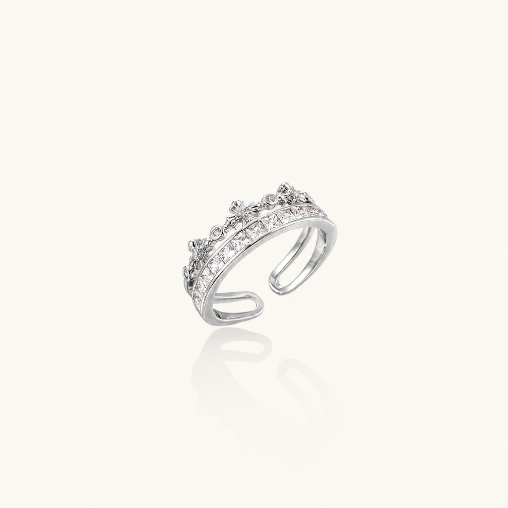 Silver-toned adjustable crown ring with channel-set square zirconia stones and delicate floral details on white background