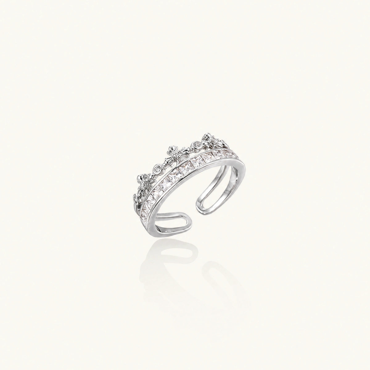 Silver-toned adjustable crown ring with channel-set square zirconia stones and delicate floral details on white background